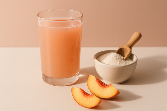 Klarer Pfirsich-Kollagendrink neben einer Schale Kollagenpulver mit Löffel und Pfirsichscheiben